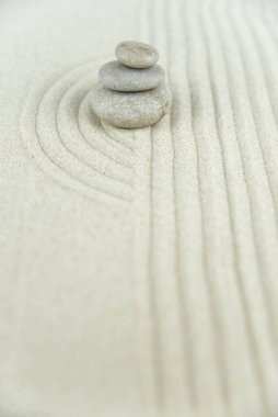 Zen bahçesi. Beyaz ve gri Zen taşlarından piramitler soyut dalga çizimleriyle beyaz kumun üzerinde. Uyum kavramı, denge ve meditasyon, spa, masaj, rahatlama.