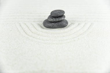 Zen bahçesi. Beyaz ve gri Zen taşlarından piramitler soyut dalga çizimleriyle beyaz kumun üzerinde. Uyum kavramı, denge ve meditasyon, spa, masaj, rahatlama.