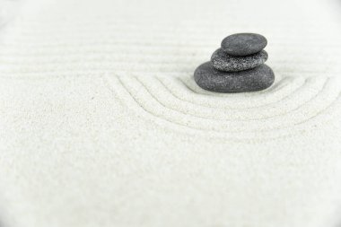 Zen bahçesi. Beyaz ve gri Zen taşlarından piramitler soyut dalga çizimleriyle beyaz kumun üzerinde. Uyum kavramı, denge ve meditasyon, spa, masaj, rahatlama.