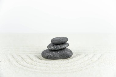 Zen bahçesi. Beyaz ve gri Zen taşlarından piramitler soyut dalga çizimleriyle beyaz kumun üzerinde. Uyum kavramı, denge ve meditasyon, spa, masaj, rahatlama.