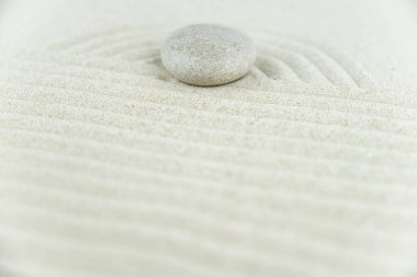Zen bahçesi. Beyaz ve gri Zen taşlarından piramitler soyut dalga çizimleriyle beyaz kumun üzerinde. Uyum kavramı, denge ve meditasyon, spa, masaj, rahatlama.