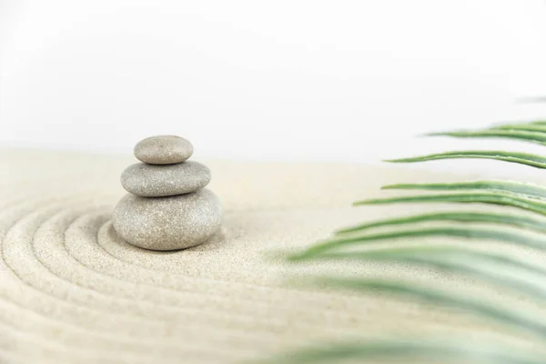 Zen bahçesi. Beyaz ve gri Zen taşlarından piramitler soyut dalga çizimleriyle beyaz kumun üzerinde. Uyum kavramı, denge ve meditasyon, spa, masaj, rahatlama.