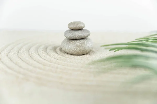 Zen bahçesi. Beyaz ve gri Zen taşlarından piramitler soyut dalga çizimleriyle beyaz kumun üzerinde. Uyum kavramı, denge ve meditasyon, spa, masaj, rahatlama.