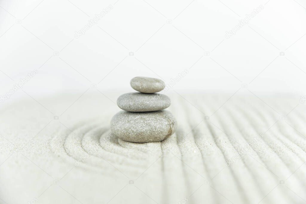 Zen garden. Pyramids of white and gray zen stones on the white sand with abstract wave drawings. Concept of harmony, balance and meditation, spa, massage, relax.