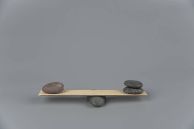 Denge, dengesizlik ve dengesizlik. Tahta tahtadan tahterevallide Zen taşları. Uyum, sakinlik, yoga ve meditasyon, spa, masaj, rahatlama. Zen bahçesi.