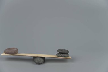 Denge, dengesizlik ve dengesizlik. Tahta tahtadan tahterevallide Zen taşları. Uyum, sakinlik, yoga ve meditasyon, spa, masaj, rahatlama. Zen bahçesi.