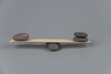 Denge, dengesizlik ve dengesizlik. Tahta tahtadan tahterevallide Zen taşları. Uyum, sakinlik, yoga ve meditasyon, spa, masaj, rahatlama. Zen bahçesi.