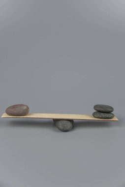 Denge, dengesizlik ve dengesizlik. Tahta tahtadan tahterevallide Zen taşları. Uyum, sakinlik, yoga ve meditasyon, spa, masaj, rahatlama. Zen bahçesi.