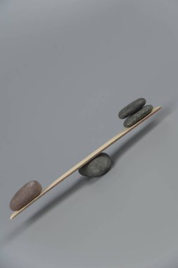 Denge, dengesizlik ve dengesizlik. Tahta tahtadan tahterevallide Zen taşları. Uyum, sakinlik, yoga ve meditasyon, spa, masaj, rahatlama. Zen bahçesi.