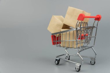 Alış veriş arabası, paketler ve kutular, modaya uygun gri arka planda, kopya alanı izole edilmiş. Çevrimiçi alışveriş ve satış kavramı.