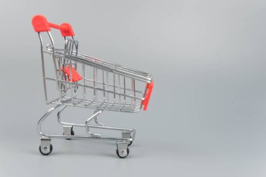 Moda gri arka planda fotokopi alanı olan boş alışveriş arabasının yakın plan görüntüsü 