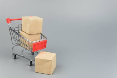 Alış veriş arabası, paketler ve kutular, modaya uygun gri arka planda, kopya alanı izole edilmiş. Çevrimiçi alışveriş ve satış kavramı.