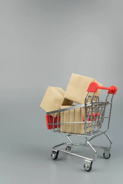 Shopping cart with purchases - packages and boxes on trendy gray background with copy space isolated. Online shopping and sale concept.