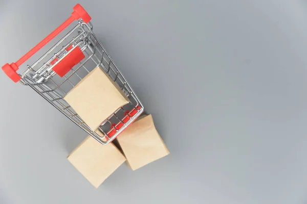 Shopping cart with purchases - packages and boxes on trendy gray background with copy space isolated. Online shopping and sale concept.