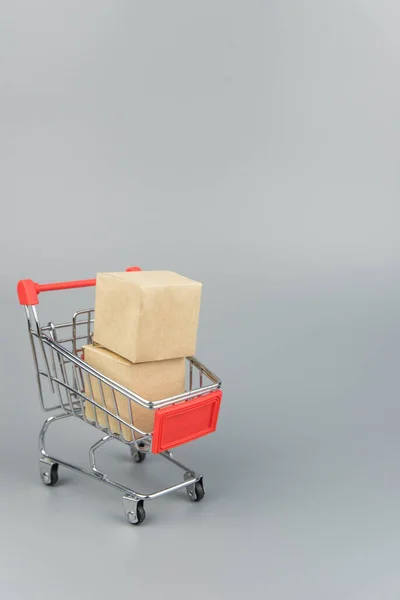 Shopping cart with purchases - packages and boxes on trendy gray background with copy space isolated. Online shopping and sale concept.