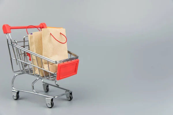 Shopping cart with purchases - packages and boxes on trendy gray background with copy space isolated. Online shopping and sale concept.