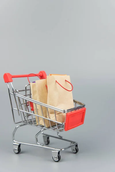 Shopping cart with purchases - packages and boxes on trendy gray background with copy space isolated. Online shopping and sale concept.