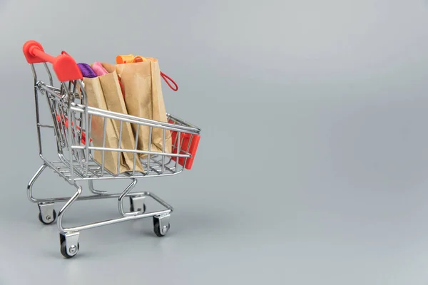 Shopping cart with purchases - packages and boxes on trendy gray background with copy space isolated. Online shopping and sale concept.