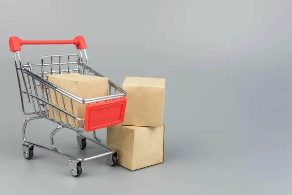 Shopping cart with purchases - packages and boxes on trendy gray background with copy space isolated. Online shopping and sale concept.