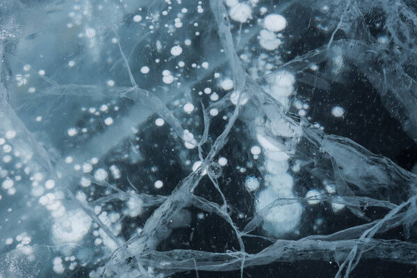 Ice texture close-up. Frozen Baikal lake in Siberia. Beautiful cracked ice with air and methane bubbles. 