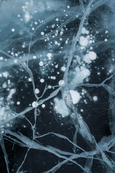 Ice texture close-up. Frozen Baikal lake in Siberia. Beautiful cracked ice with air and methane bubbles. 