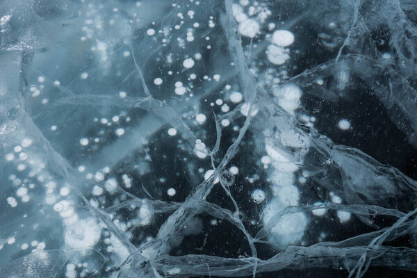 Ice texture close-up. Frozen Baikal lake in Siberia. Beautiful cracked ice with air and methane bubbles. 