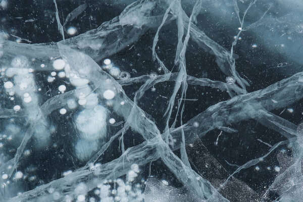Ice texture close-up. Frozen Baikal lake in Siberia. Beautiful cracked ice with air and methane bubbles. 