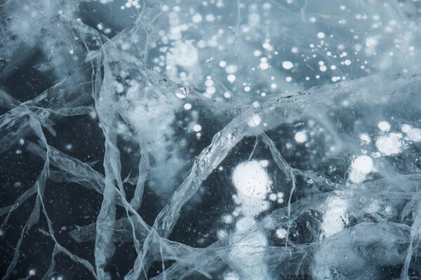 Ice texture close-up. Frozen Baikal lake in Siberia. Beautiful cracked ice with air and methane bubbles. 