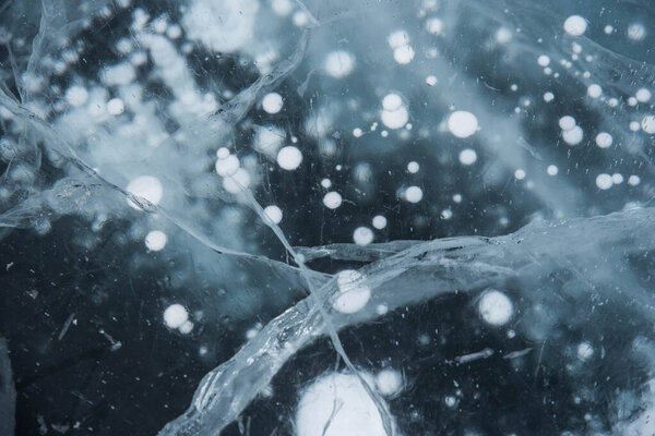 Ice texture close-up. Frozen Baikal lake in Siberia. Beautiful cracked ice with air and methane bubbles. 