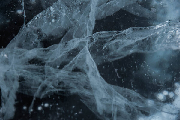 Ice texture close-up. Frozen Baikal lake in Siberia. Beautiful cracked ice with air and methane bubbles. 