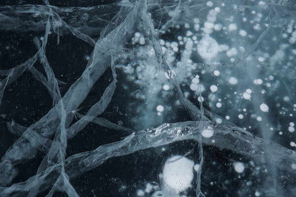 Ice texture close-up. Frozen Baikal lake in Siberia. Beautiful cracked ice with air and methane bubbles. 
