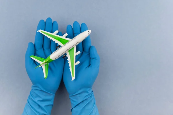 Safe travels concept. Plane in hands in medical gloves. Safety flight and travel during quarantine and lockdown.