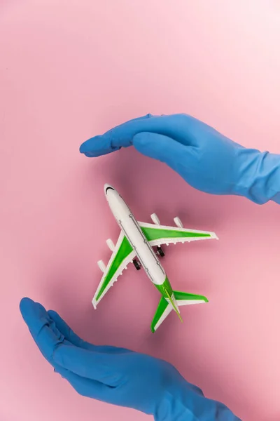 Safe travels concept. Plane in hands in medical gloves. Safety flight and travel during quarantine and lockdown.