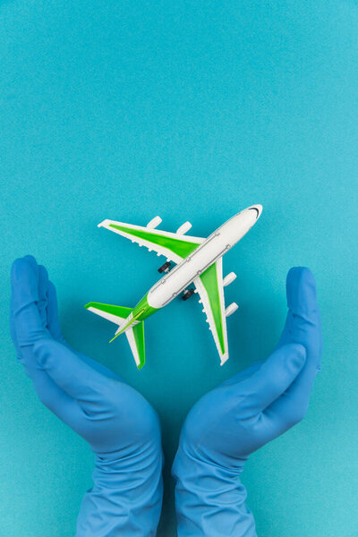 Safe travels concept. Plane in hands in medical gloves. Safety flight and travel during quarantine and lockdown.