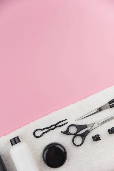 Professional hair dresser tools with copy space. Hair stylist equipment set on pink background. Scissors, brush, hairbrush, balm flat lay top view.