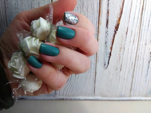 beautiful green manicure on a wooden texture