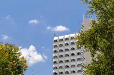 Çok katlı bina, ağaçlar, mavi gökyüzü bulutlu