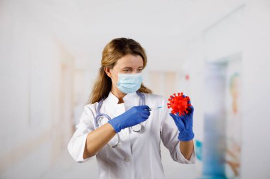 Maskeli bir kadın doktor 2019-nCoV (SARS-CoV-2) modeli bulundurur. Çin koronavirüs hastalığı COVID-19 tehlikelidir.