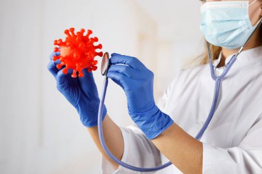 Maskeli bir kadın doktor 2019-nCoV (SARS-CoV-2) modeli bulundurur. Çin koronavirüs hastalığı COVID-19 tehlikelidir.