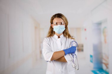 Kolları çapraz duran, tıbbi maske takan kendine güvenen kadın doktor. kadın portresi.