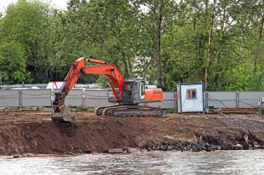 nehir kıyısında karada kazma turuncu Paletli ekskavatör