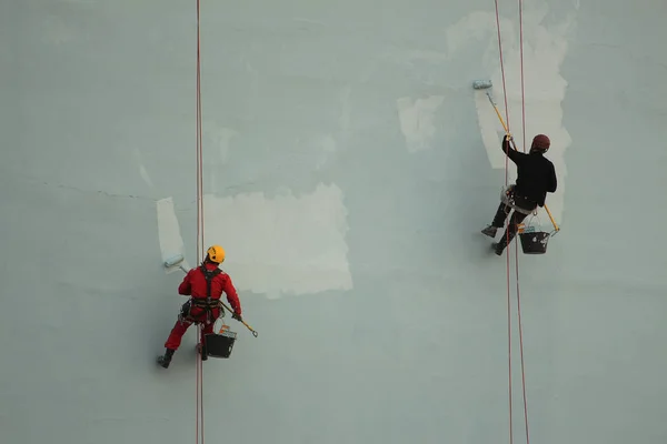 Industrial climbers paint the wall of the building