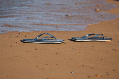 Su kenarındaki kum üzerinde parmak arası terlik