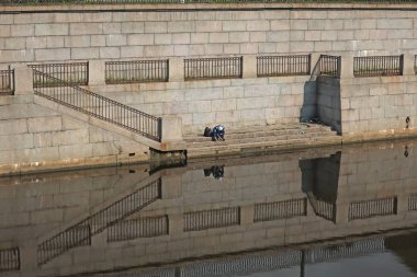 Granit bir iskelede bir rıhtımda oturan bir adam