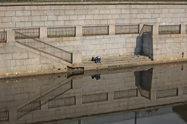 Granit bir iskelede bir rıhtımda oturan bir adam