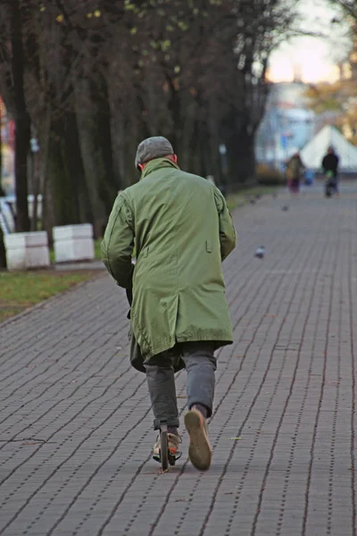 Człowiek Zielony Płaszcz Jazda Skuterem Jesień Boulevard — Zdjęcie stockowe