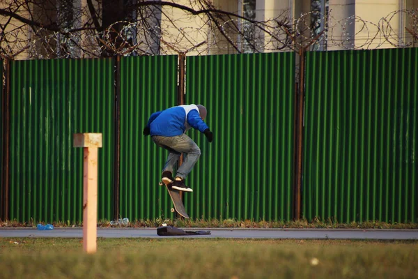 滑板运动员在绿色栅栏旁的滑板上弹跳 — 图库照片