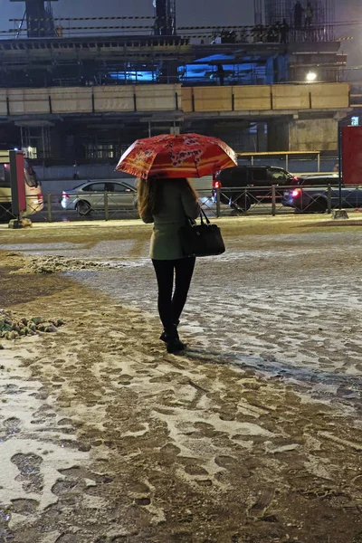 Genç kadın şemsiye ile akşam yağan kar altında bekliyor