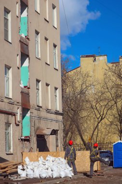 iki işçi inşaat sahasında üst katlarda bir ip üzerinde yük Asansör