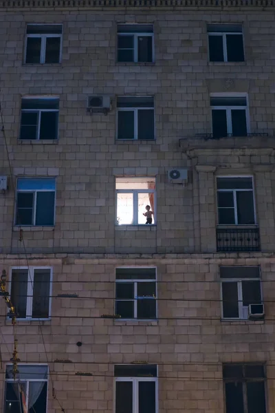 akşam bir apartmanın ışıklı penceresinde bir çocuğun silueti